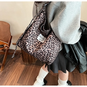 Detail of leopard print canvas tote bag with Muheti logo label worn as crossbody bag