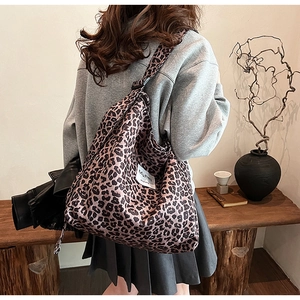 Detail of leopard print corduroy tote bag with brand logo label on model shoulder