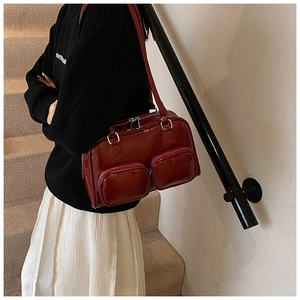 Detailed view of wine red glossy leather shoulder bag with double front zip pockets