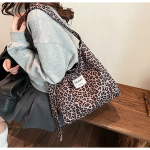Detailed view of leopard print canvas tote bag with Muheti label worn by model