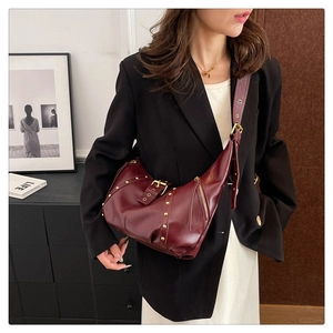 Détail du sac hobo en cuir bordeaux avec rivets dorés et bandoulière réglable