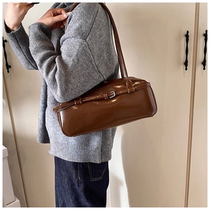 Close-up of brown PU leather baguette bag with buckle detail worn by a model