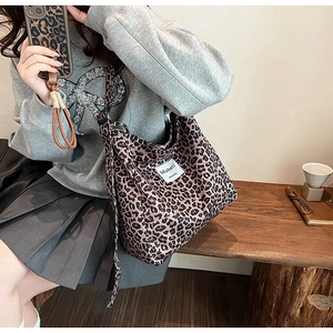 Detailed view of leopard print canvas tote bag with wide strap and Muheti woven label tag