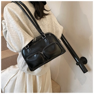 Detail of glossy black shoulder bag featuring dual front pockets and sleek patent finish