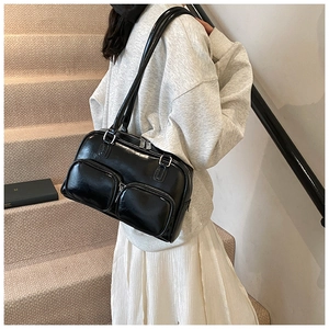 Detail view of stylish black faux leather shoulder bag with dual front zipper pockets