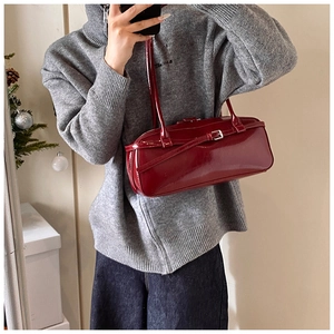 Detail of burgundy glossy patent leather shoulder bag styled for winter holiday outfits