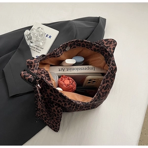Macro shot of large leopard print tote bag interior capacity with books and accessories