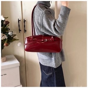 Detail of a dark red glossy rectangular shoulder bag with silver buckle and retro style