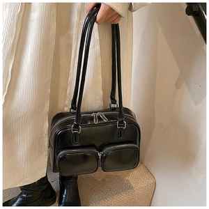 Close-up of black glossy faux leather shoulder bag with double pockets and silver zippers