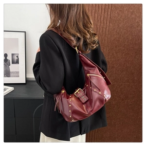 Détail du sac demi-lune en cuir rouge avec clous dorés et bandoulière réglable