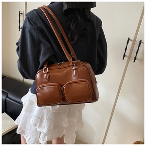Close-up of brown glossy leather underarm bag with double front zippers on shoulder