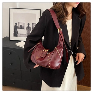 Détail du sac hobo en cuir bordeaux avec rivets dorés et boucle de ceinture vintage