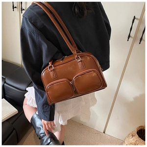 Detail view of a vintage brown shoulder bag with dual zipper pockets on a female model