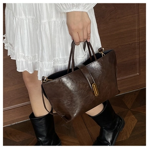 Détail du sac cabas marron foncé vintage montrant la texture brillante et boucle d'or