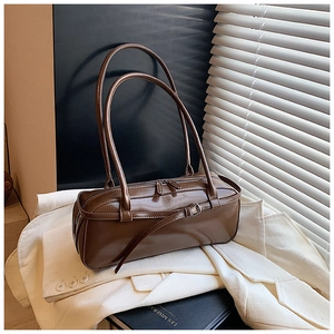 Brown vintage patent leather shoulder bag placed on an elegant beige blazer