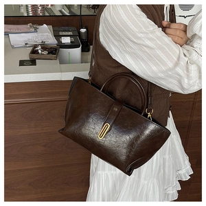 Detail of vintage dark brown tote bag showing glossy cracked texture and golden hardware buckle