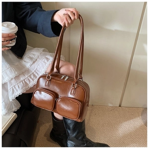 Close-up of caramel leather shoulder bag featuring two practical front zip pockets