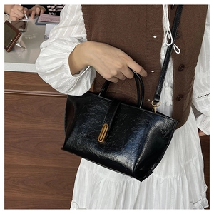 Détail d'un sac cabas vintage noir avec texture craquelée brillante et boucle dorée