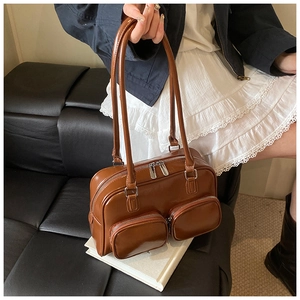 Detail view of caramel brown faux leather shoulder bag with functional zippers on books