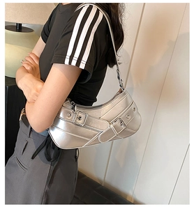 Detail of silver metallic crescent bag featuring buckled straps and metal eyelets