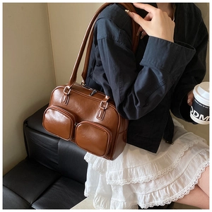 Detail shot of a brown vintage shoulder bag featuring dual front pockets and silver hardware