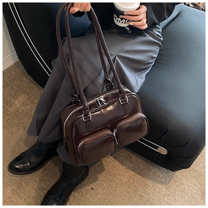Detail of dark brown glossy shoulder bag with dual front zipper pockets and shiny finish