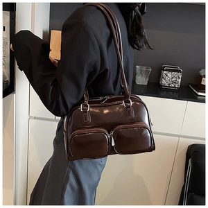 Detail of dark brown glossy patent leather shoulder bag with two front zipper pockets