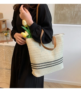 Detail of woven tote bag with black stripes, leather handles, and spacious interior