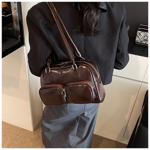 Detailed view of dark brown glossy underarm bag featuring dual front zipper pockets