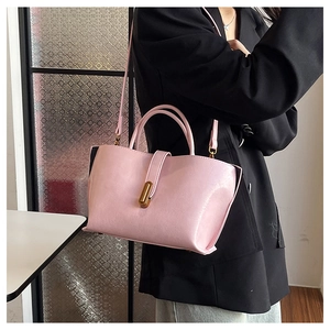 Détail d'un sac à main en cuir verni rose avec une boucle métallique dorée élégante