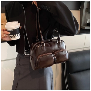 Detail of dark brown glossy leather shoulder bag with two front zipper pockets