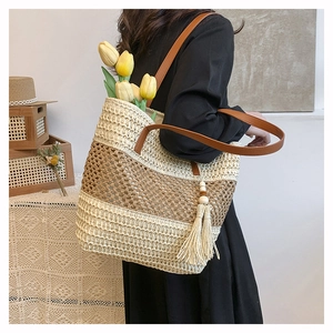 Close-up of woven straw bag with contrasting stripes, leather strap and tassel detail