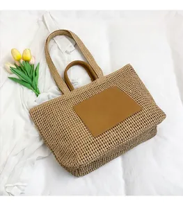 Detail of hand-woven straw tote with dual leather handles and brown square patch