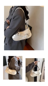 Detailed view of cream-colored shoulder bag with multiple buckles and metal rivets