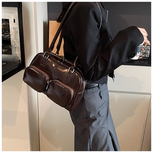 Detail of dark brown glossy leather shoulder bag with functional double front pockets