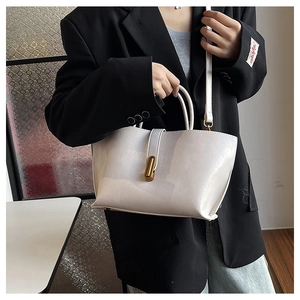 Sac cabas chic en cuir verni crème avec fermoir doré porté sur une tenue de bureau