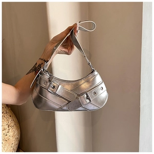 Detail of silver metallic motor-style baguette bag with buckle straps and eyelet accents