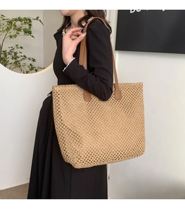 Close-up of summer woven straw tote bag with brown leather handles worn by a model