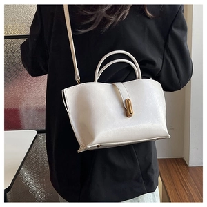 Detail view of the elegant white leather tote bag with a polished gold metal lock buckle