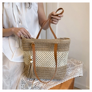 Detail of hand-woven straw tote bag featuring contrast stripes and white beaded tassels