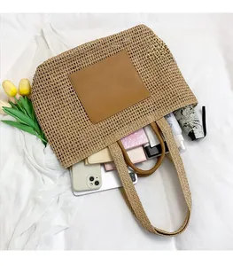 Top view of large straw tote bag with brown leather patch showing spacious interior items