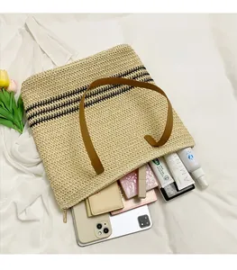 Top view of woven straw tote bag with black stripes and brown faux leather straps