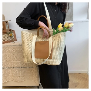 Detail of hollow straw tote bag with brown leather handles for summer vacation use