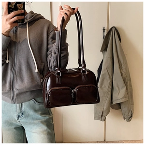 Detail of glossy chocolate brown shoulder bag with dual front zipper pockets