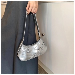 Detailed view of silver metallic underarm bag featuring decorative buckles and punk style