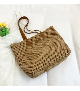 Detail view of woven straw beach bag with dark brown faux leather straps and mesh pattern