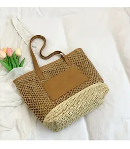 Detail of woven straw tote bag featuring leather handles and a two-tone paper rope design