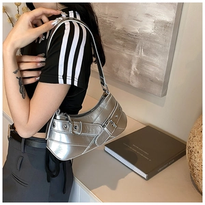 Close-up of metallic silver Y2K shoulder bag featuring industrial eyelets and buckle details
