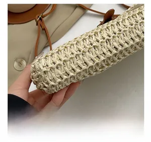 Detail of the woven texture and brown leather strap with bronze buckle on straw bag