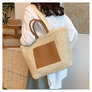 Detail shot of the woven straw texture and premium brown leather patch on this summer tote bag